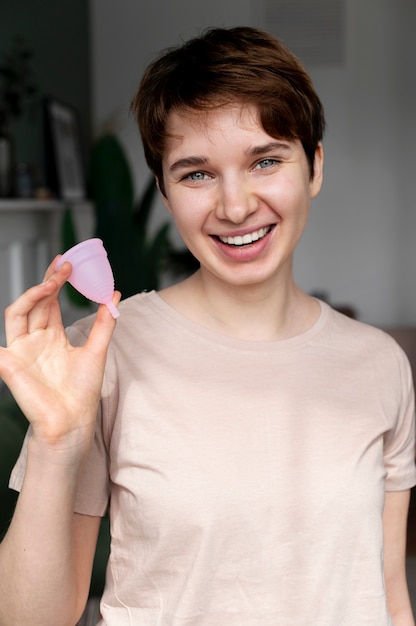Mujer sonriente sosteniendo copa menstrual tiro medio