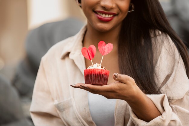 Mujer sonriente sosteniendo un cupcake de San Valentín