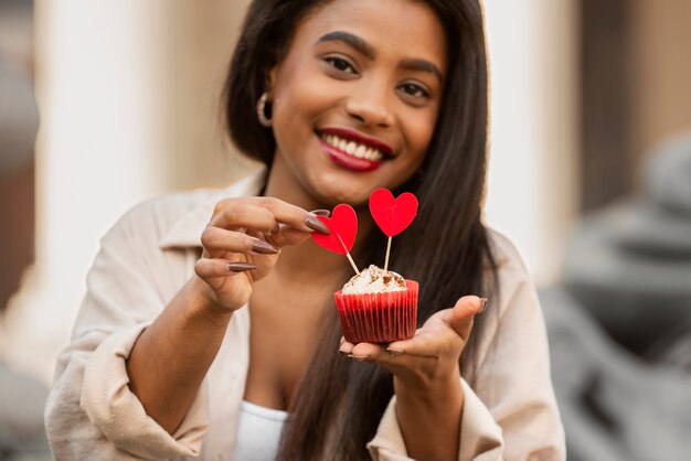 Mujer sonriente sosteniendo un cupcake de San Valentín