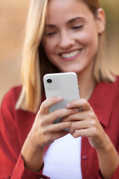 Mujer sonriente sosteniendo el dispositivo de cerca