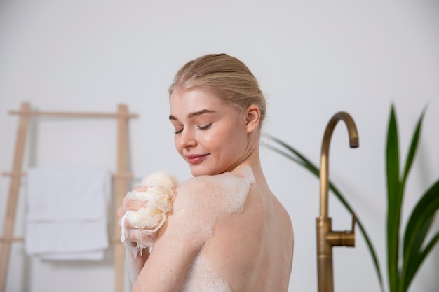 Mujer sonriente sosteniendo una esponja de baño de cerca