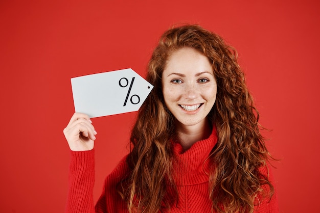 Mujer sonriente sosteniendo etiqueta de precio en blanco