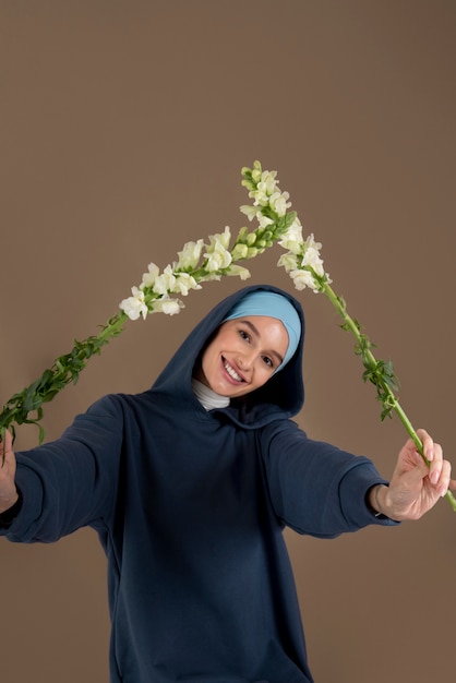 Foto gratuita mujer sonriente sosteniendo flores tiro medio