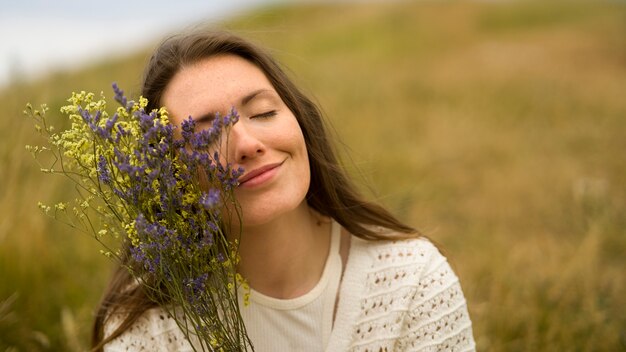 Mujer sonriente sosteniendo flores vista frontal