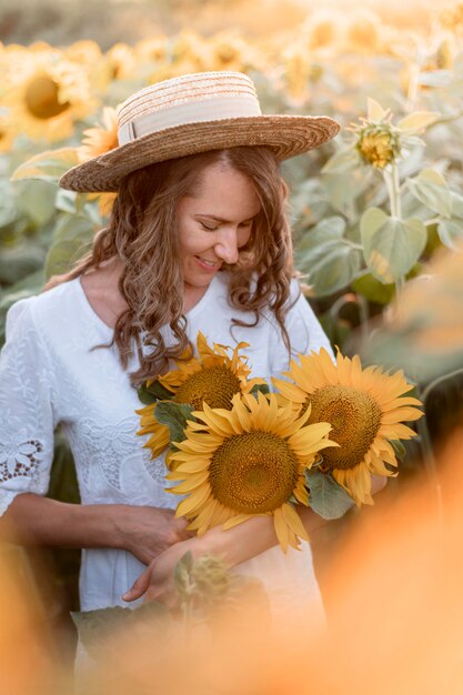 Mujer sonriente sosteniendo girasoles