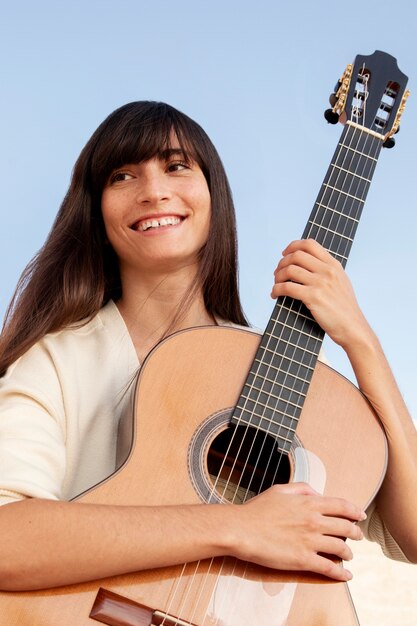 Mujer sonriente sosteniendo la guitarra de cerca