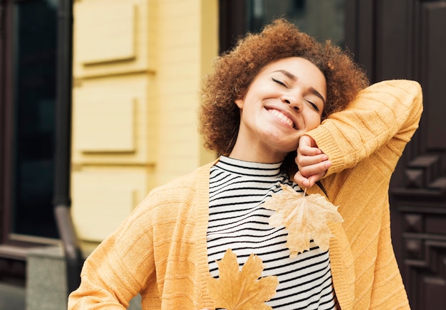 Foto gratuita mujer sonriente sosteniendo hojas al aire libre