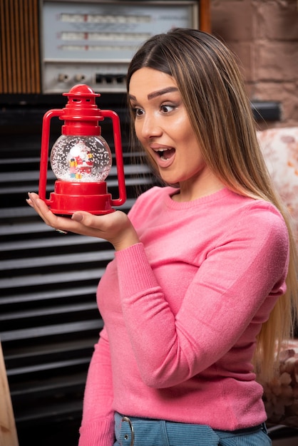 Foto gratuita una mujer sonriente sosteniendo una lámpara roja de navidad. foto de alta calidad