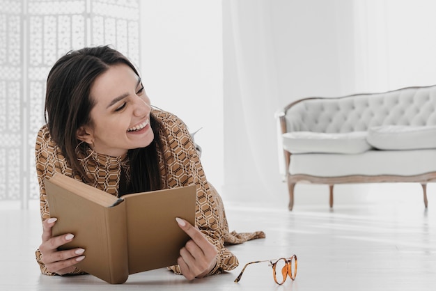 Mujer sonriente sosteniendo libro en casa