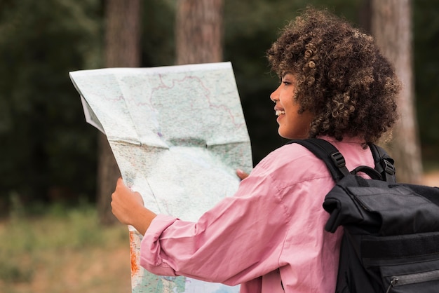 Foto gratuita mujer sonriente sosteniendo mapa mientras acampa al aire libre