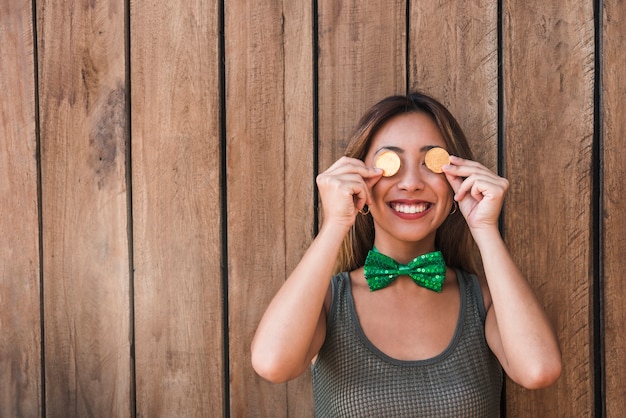 Foto gratuita mujer sonriente sosteniendo monedas de oro cerca de los ojos