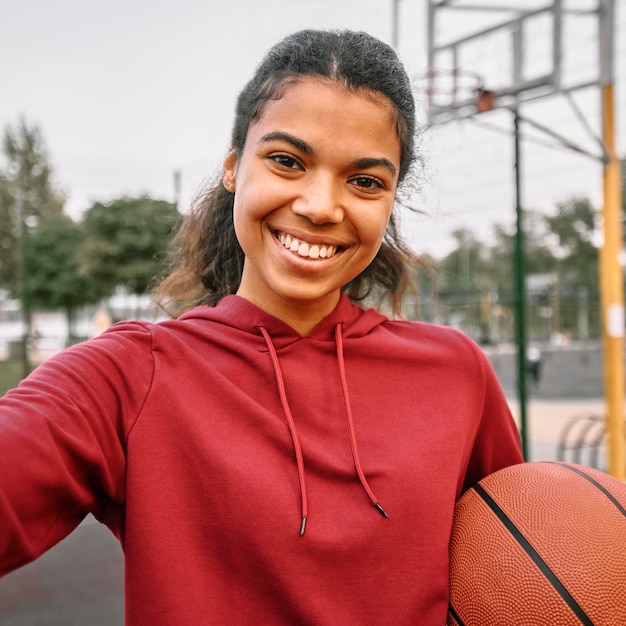 Mujer sonriente sosteniendo una pelota de baloncesto