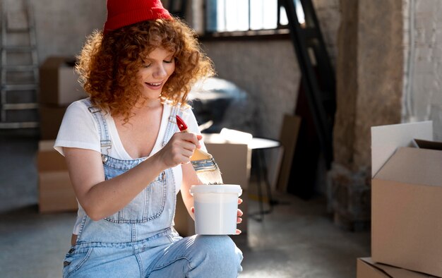 Mujer sonriente sosteniendo un pincel y un cubo para la nueva decoración del hogar