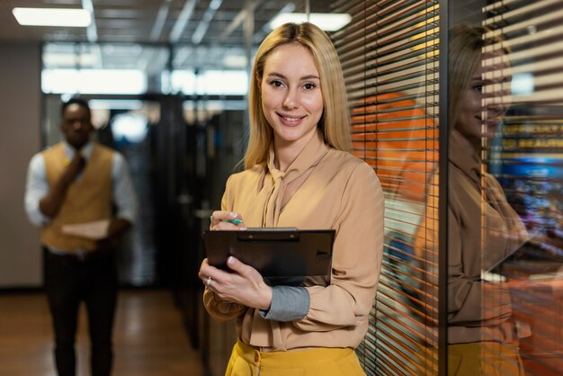 Mujer sonriente sosteniendo portapapeles en el lugar de trabajo