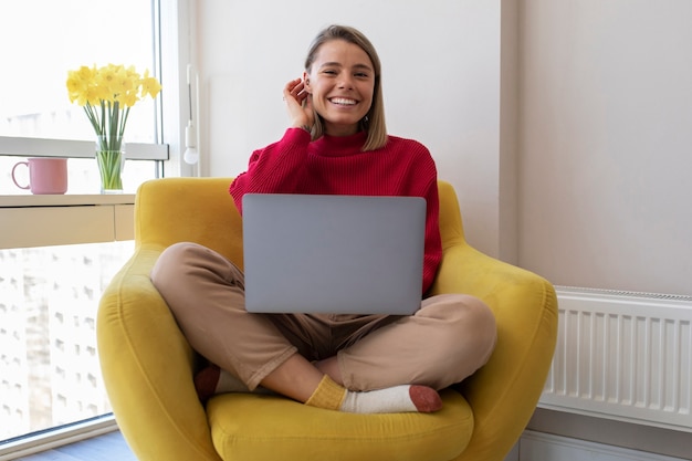 Mujer sonriente sosteniendo un portátil de tiro completo