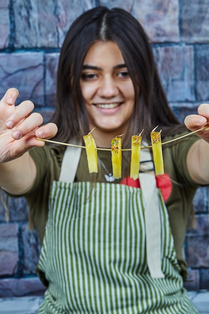 Foto gratuita una mujer sonriente sosteniendo rodajas de piña sobre fondo azul.