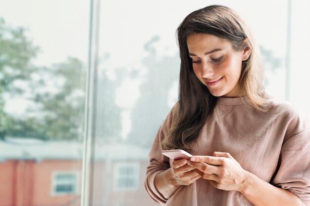 Mujer sonriente sosteniendo smartphone multimedia remezclada