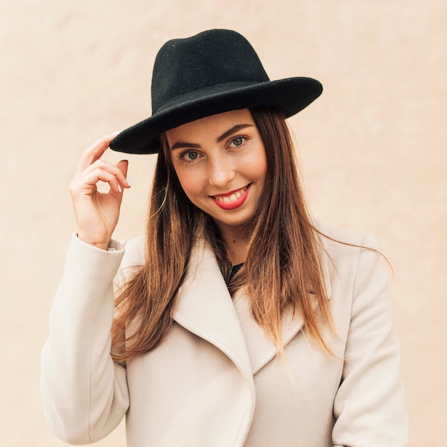 Mujer sonriente sosteniendo su sombrero