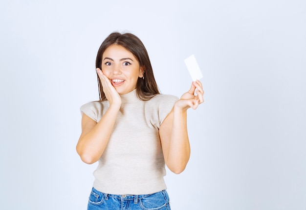 Mujer sonriente sosteniendo una tarjeta sobre fondo blanco.