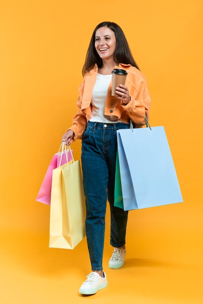 Mujer sonriente sosteniendo una taza de café y un montón de bolsas de la compra.