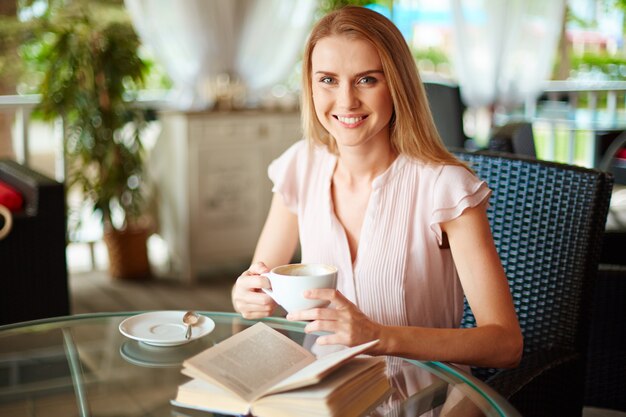 Mujer sonriente sosteniendo una taza de café en sus manos