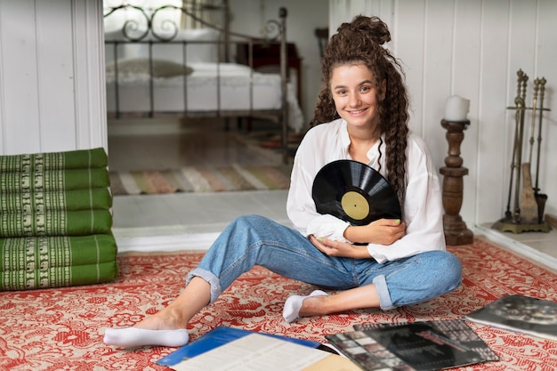 Foto gratuita mujer sonriente sosteniendo tiro completo de disco de vinilo