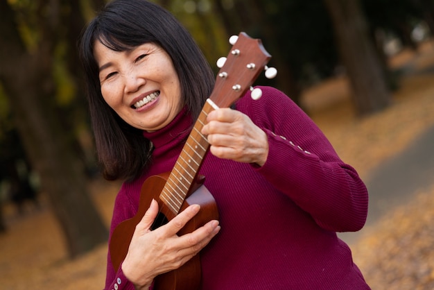 Foto gratuita mujer sonriente sosteniendo ukelele de cerca