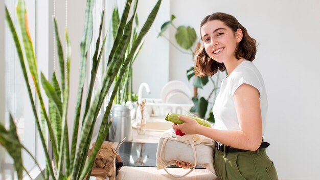 Mujer sonriente sosteniendo verduras orgánicas