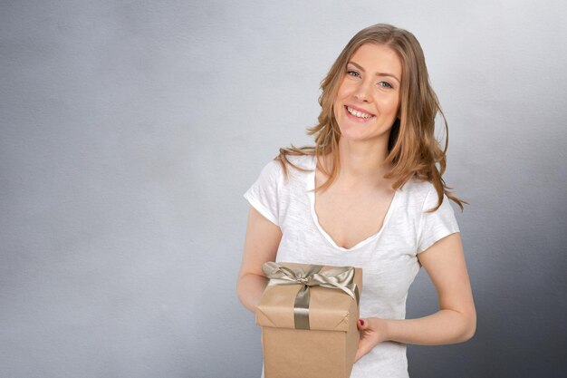 Mujer sonriente sostiene caja de regalo