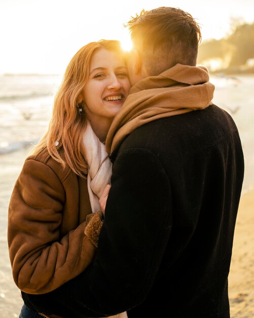 Mujer sonriente con su novio en la playa en invierno