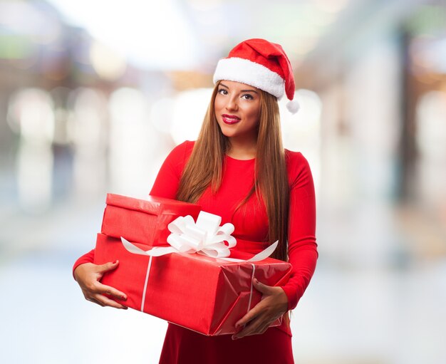 Mujer sonriente sujetando regalos con fondo borroso