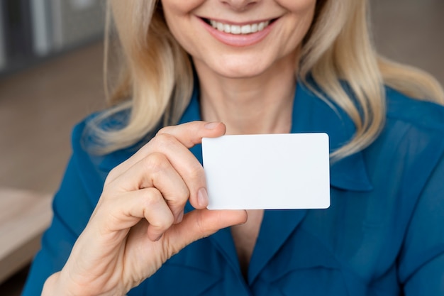 Mujer sonriente con tarjeta de visita en blanco