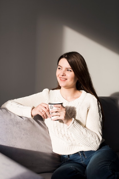 Mujer sonriente con taza en el sofá