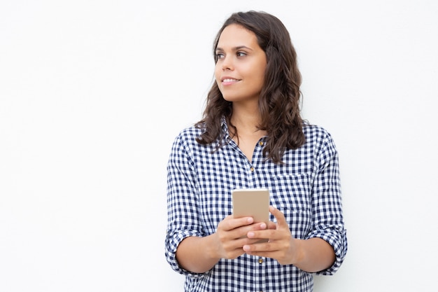 Mujer sonriente con teléfono celular mirando a un lado