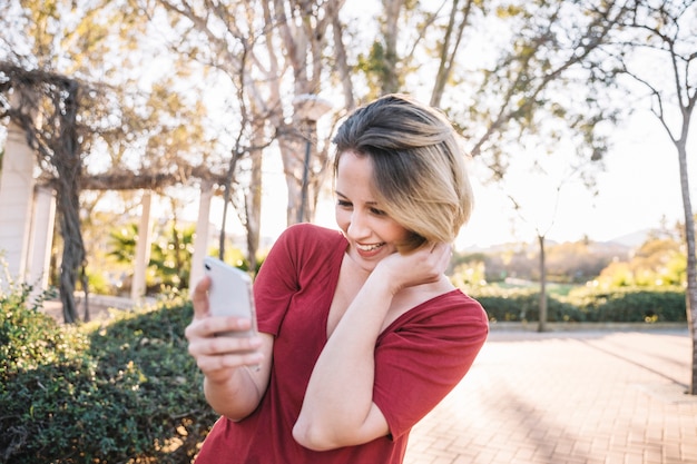 Mujer sonriente con teléfono inteligente en el parque