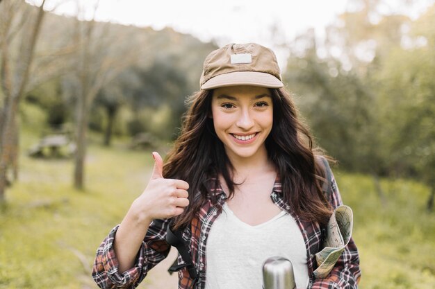 Mujer sonriente con termo gesticular pulgar arriba