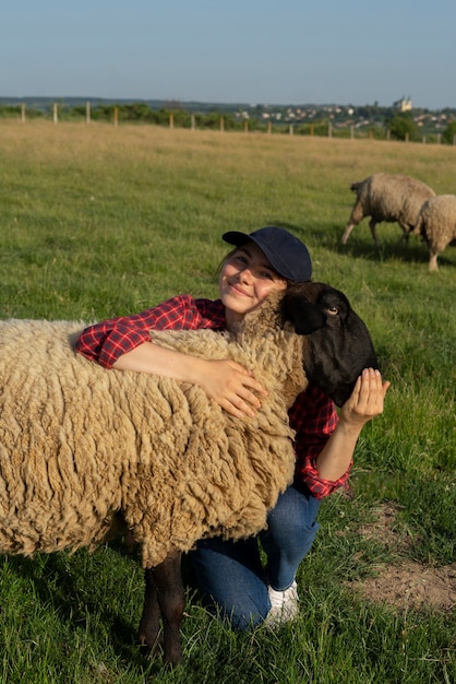 Mujer sonriente de tiro completo abrazando ovejas