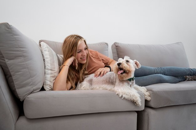 Mujer sonriente de tiro completo acariciar a perro