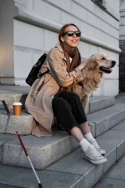 Mujer sonriente de tiro completo acariciar a perro