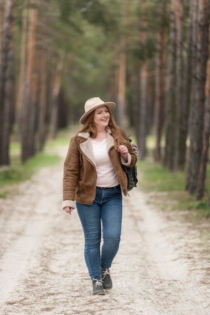Mujer sonriente de tiro completo caminando en la naturaleza
