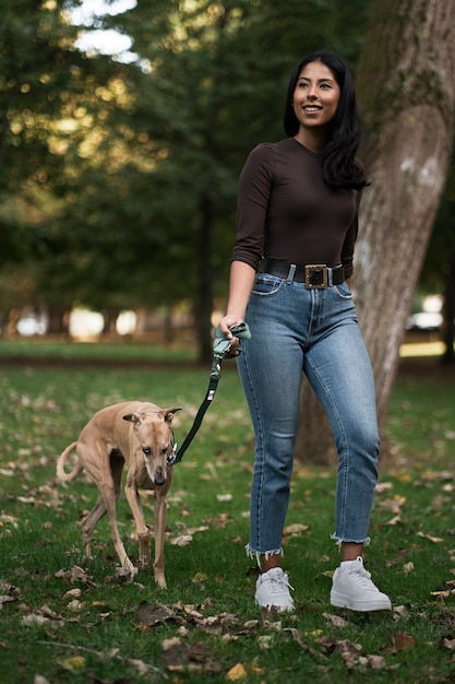 Foto gratuita mujer sonriente de tiro completo caminando con perro