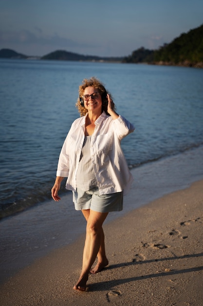 Mujer sonriente de tiro completo caminando en la playa