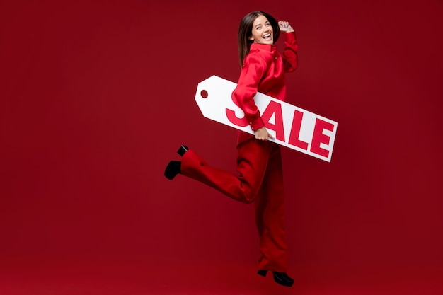 Mujer sonriente de tiro completo con cartel de venta