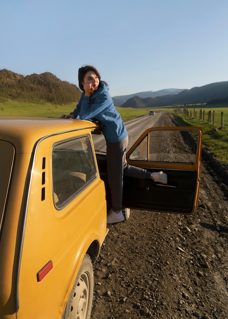 Foto gratuita mujer sonriente de tiro completo con coche