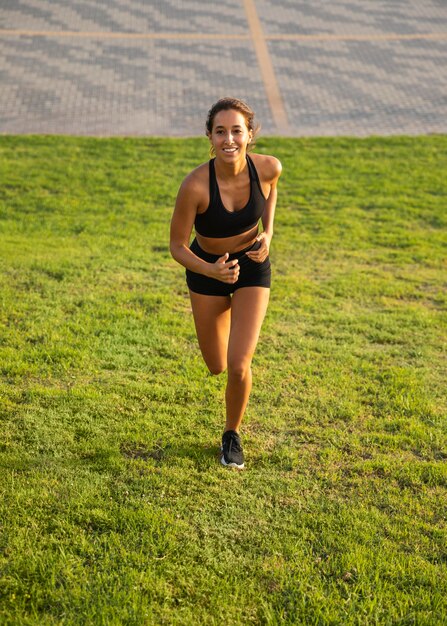 Mujer sonriente de tiro completo corriendo al aire libre