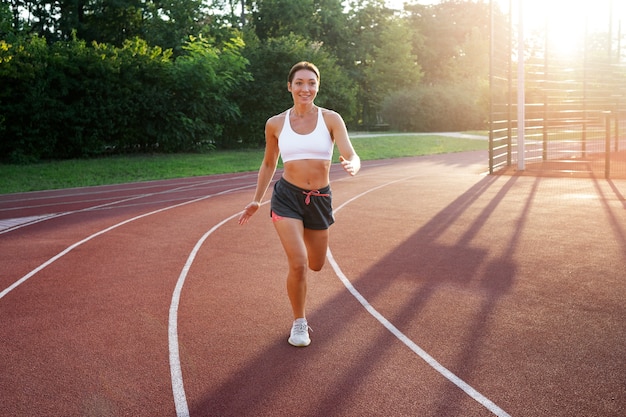 Mujer sonriente de tiro completo corriendo al aire libre