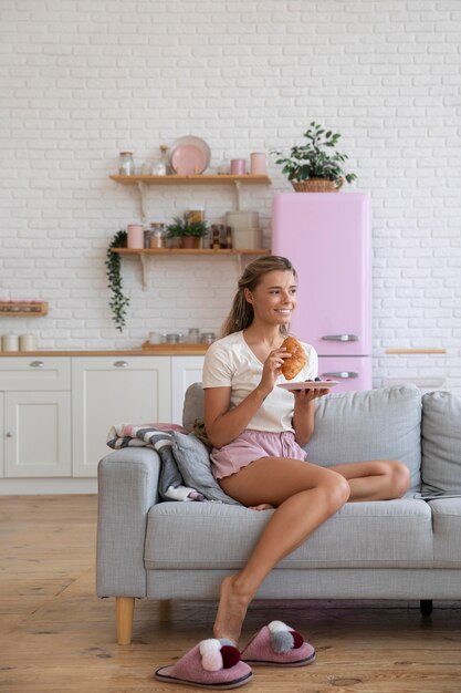 Mujer sonriente de tiro completo con croissant