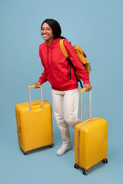 Mujer sonriente de tiro completo con equipaje amarillo