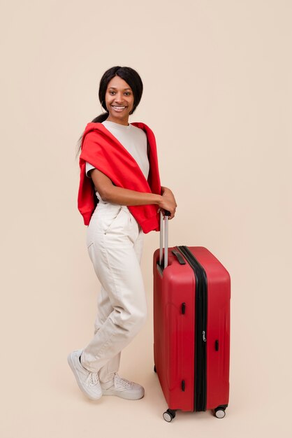 Mujer sonriente con tiro completo de equipaje rojo