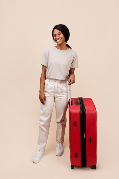 Mujer sonriente de tiro completo con equipaje rojo